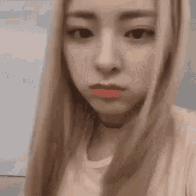 a close up of a woman 's face with long blonde hair and red lipstick .