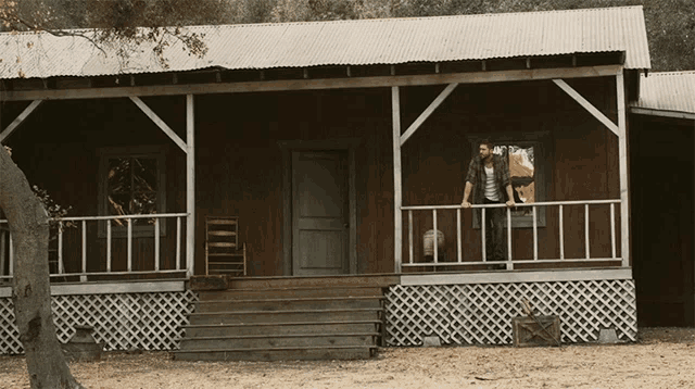 a man and woman standing on the porch of a wooden house