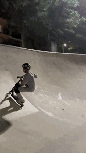 a person is riding a scooter down a ramp at a skate park