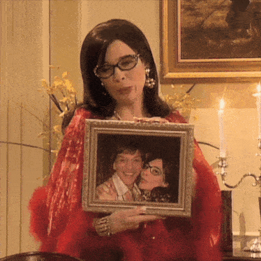 a woman holding a picture of a man and woman
