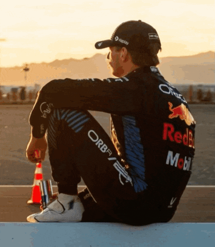 a man in a red bull outfit sits on a wall