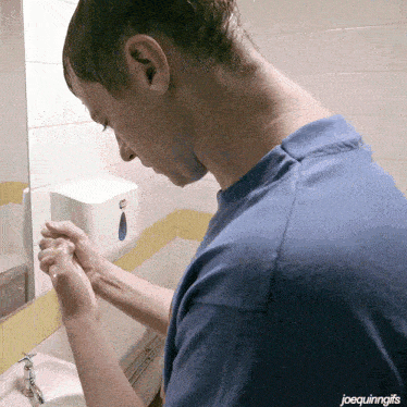 a man in a blue shirt is washing his hands