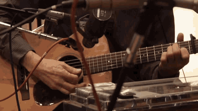 a man playing a guitar in front of a microphone that says ae