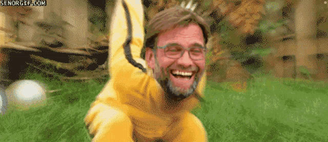 a man wearing glasses and a yellow jacket is smiling in a gif from senorgif.com
