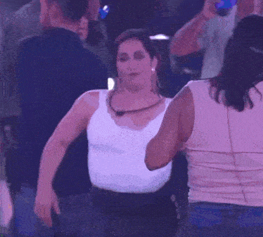 a woman in a white tank top is dancing in a club .