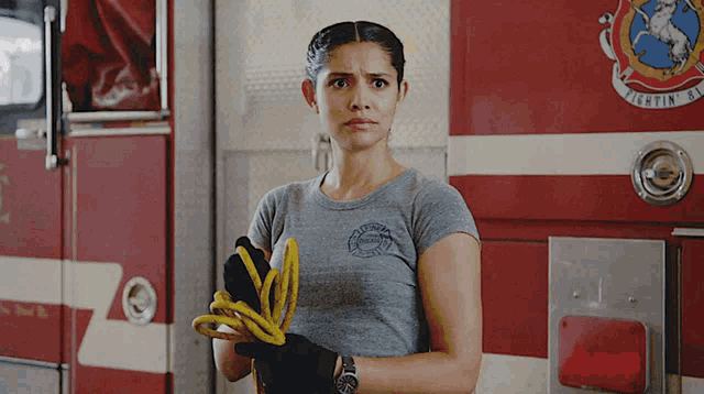 a woman stands in front of a fire truck with the word fighting on it