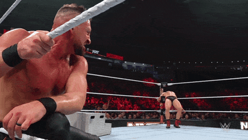 a wrestler in a wrestling ring with the word nxt on the wall