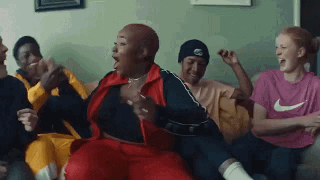 a group of people are sitting on a couch and one of them is wearing a nike shirt .