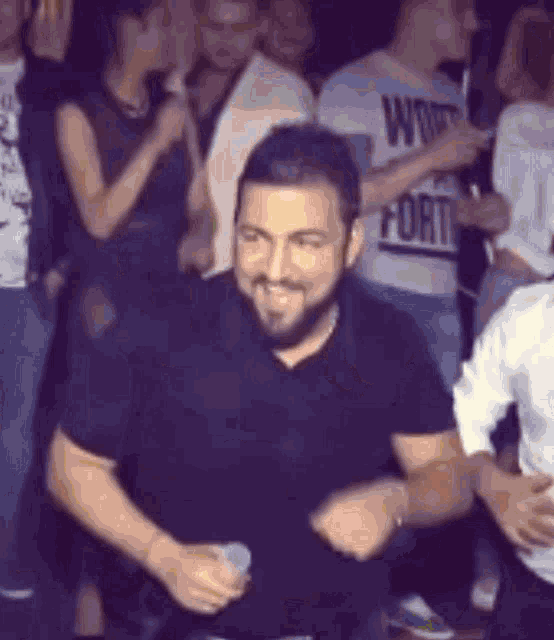 a man with a beard is dancing in a crowd at a party while holding a microphone .