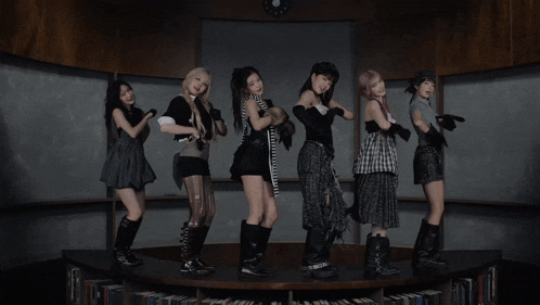 a group of girls are standing on a stage in front of a bookshelf