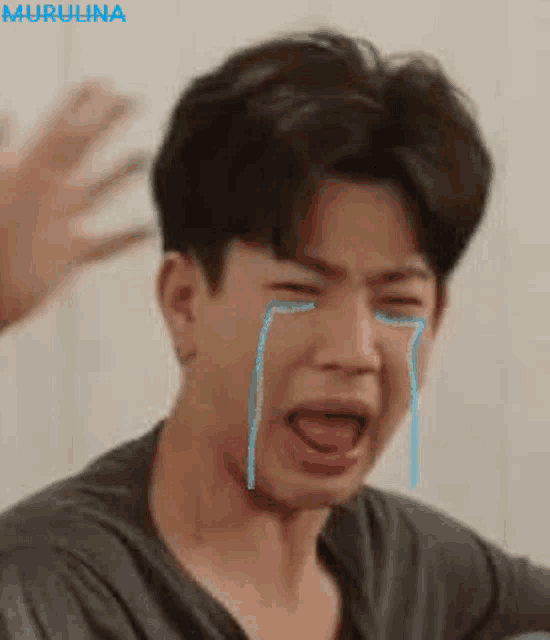 a young man is crying with tears coming out of his eyes and mouth .
