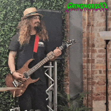 a man playing a guitar in front of a sign that says grindhorpe