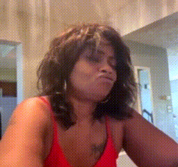 a woman in a red top is making a face .