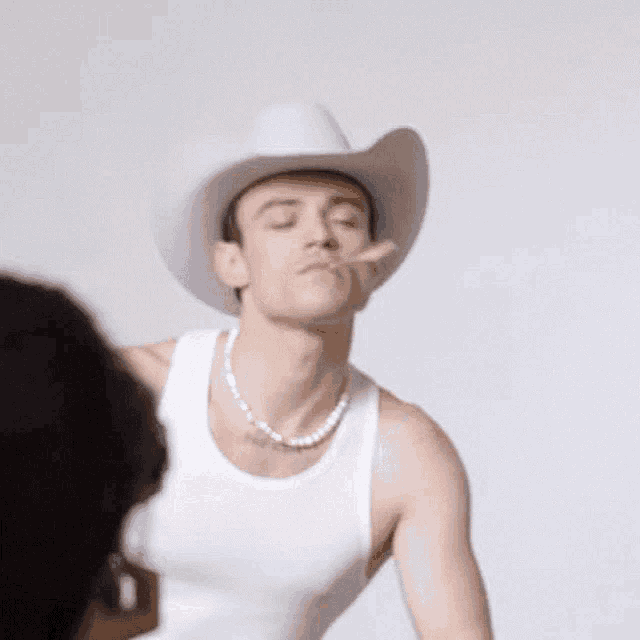 a man wearing a white cowboy hat and a white tank top