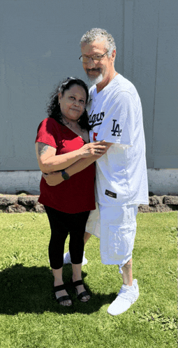a man and woman are posing for a picture and the man is wearing a dodgers jersey