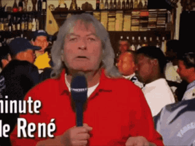 a man in a red shirt is holding a microphone in front of a crowd and says minute de rené