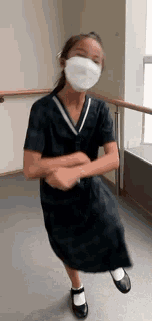 a young girl wearing a mask and a black dress is dancing .