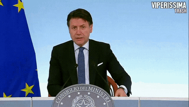 a man stands behind a podium that says consiglio dei ministri on it