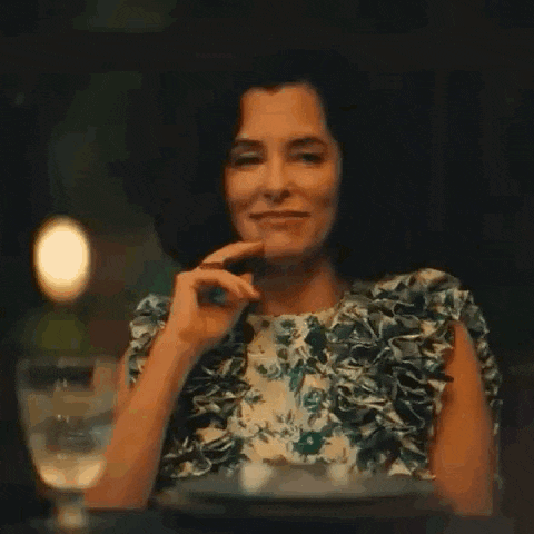 a woman in a floral dress is sitting at a table with a glass of water .