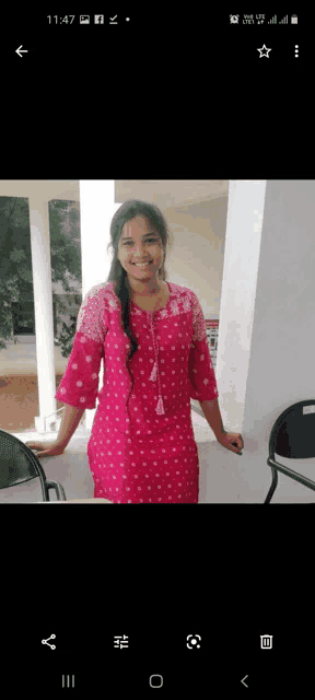 a woman in a pink dress stands in front of a white wall