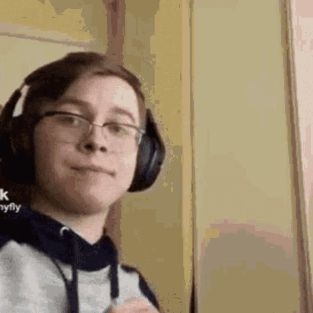 a young man wearing headphones and glasses is looking at the camera .