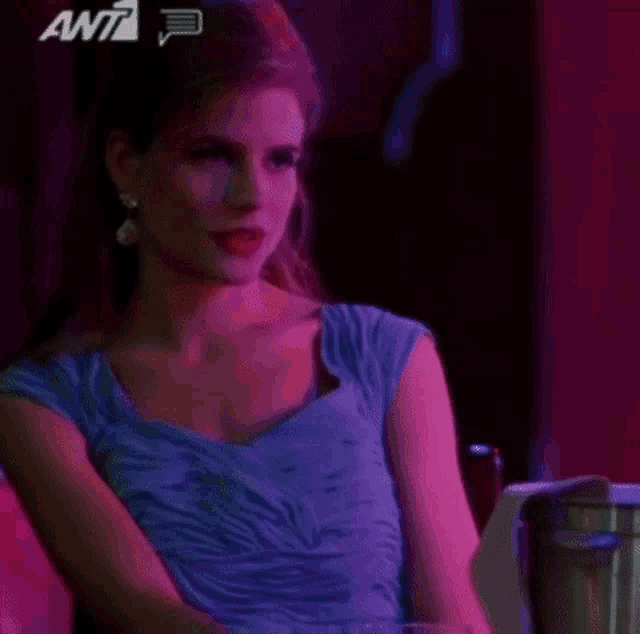 a woman in a blue dress is sitting in a chair in a dark room with purple lights .