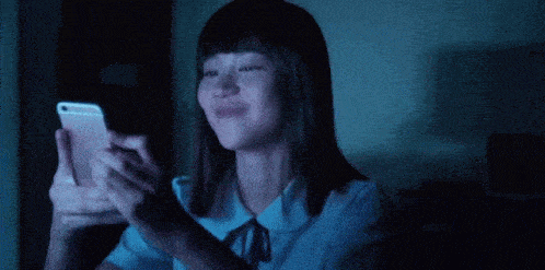 a woman is laughing while holding a cell phone in her hand .