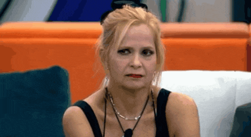 a woman is sitting on a couch wearing a black tank top and a necklace