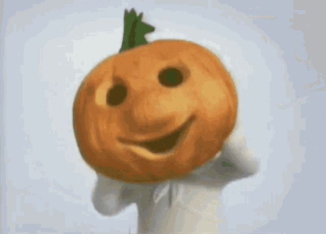 a person is holding a pumpkin in front of their face and smiling .