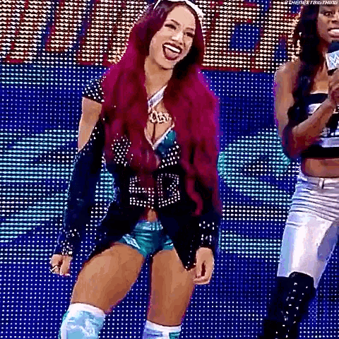 a woman with purple hair is standing on a stage in front of a crowd .
