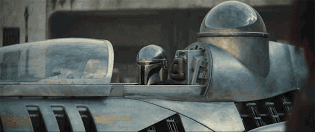 a man in a helmet sits in the cockpit of a silver vehicle