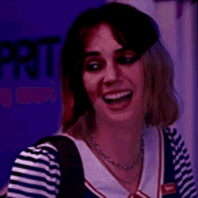 a close up of a woman wearing a striped shirt and overalls smiling .