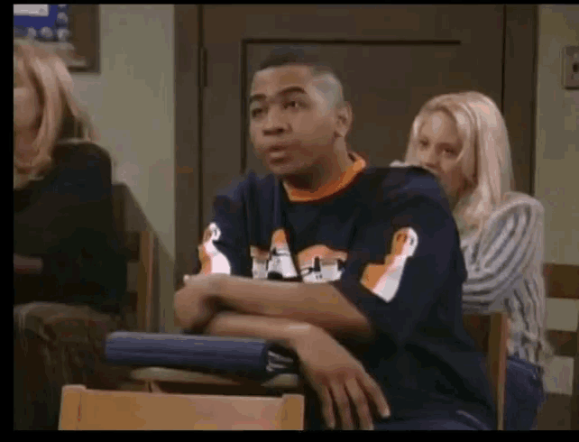 a man wearing a blue shirt with a penguin on it sits in a chair