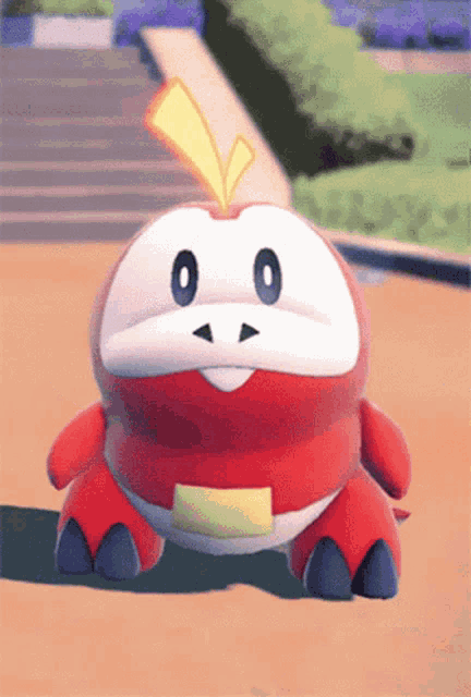 a red and white stuffed animal with a yellow arrow on its head