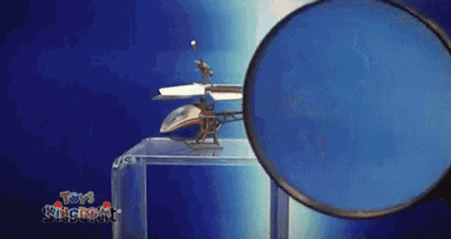 a magnifying glass is looking at a toy helicopter from the toys kingdom brand