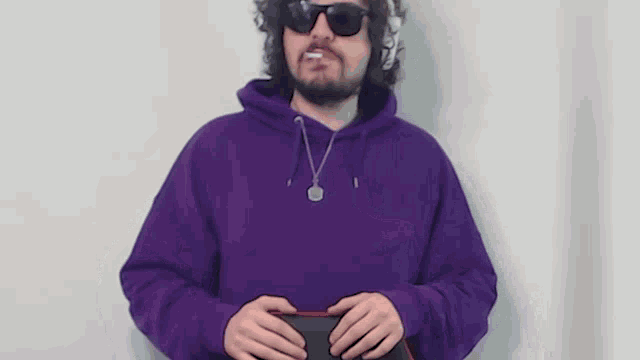 a man with a beard wearing a purple hoodie and sunglasses