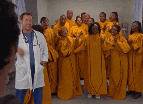 a group of people in yellow robes are singing and dancing