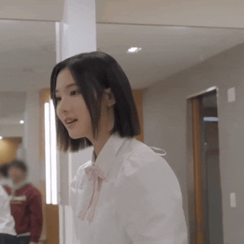 a woman wearing a white shirt and a pink bow tie is standing in front of a mirror