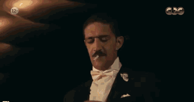 a man in a tuxedo with a cigarette in his mouth has the number 12 on the bottom right
