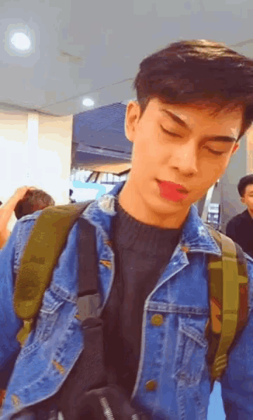a young man wearing a denim jacket with a green backpack