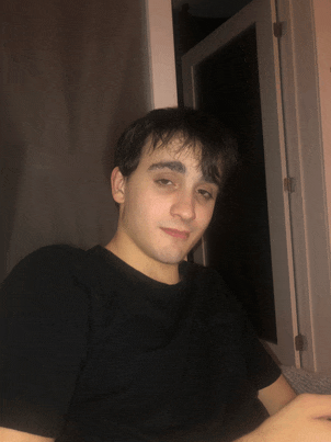 a young man in a black t-shirt looks at the camera