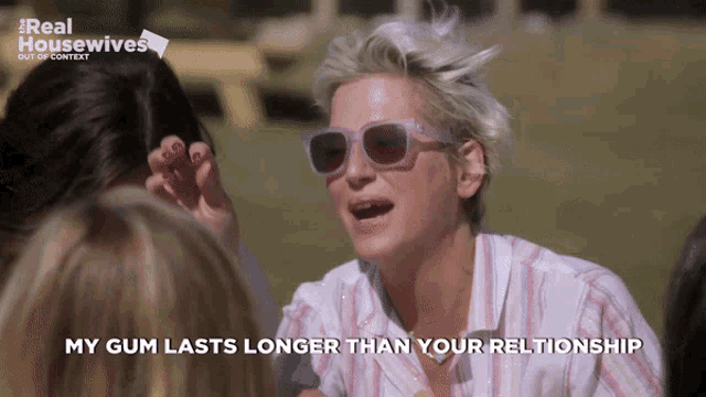 a woman wearing sunglasses says " my gum lasts longer than your relationship " in front of a group of women