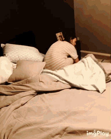 a person laying on a bed with a blanket and pillows with imgplay written below them