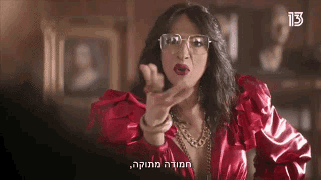 a woman in a red dress and glasses is making a gesture with her hand .