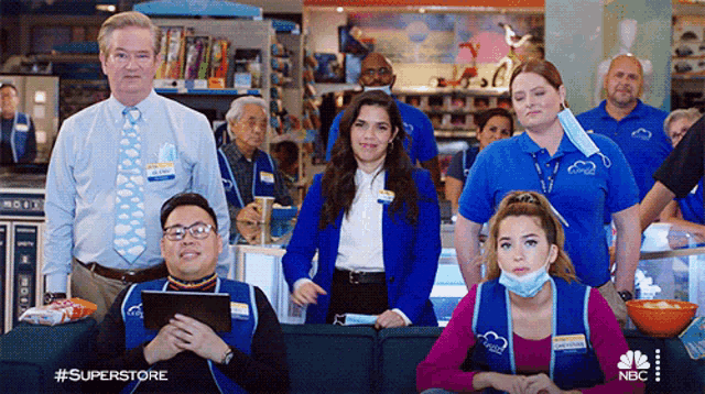 a group of superstore employees wearing face masks are sitting on a couch