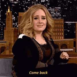 a woman is sitting in front of a building and says come back