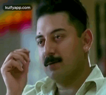 a man with a mustache is making a funny face and looking at the camera .