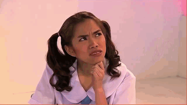 a girl with pigtails and a white shirt is making a funny face