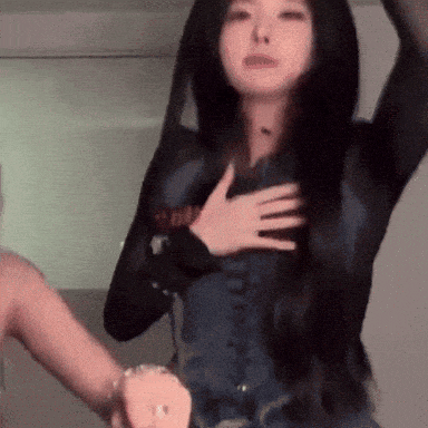 a woman with long black hair is holding her hands on her chest .