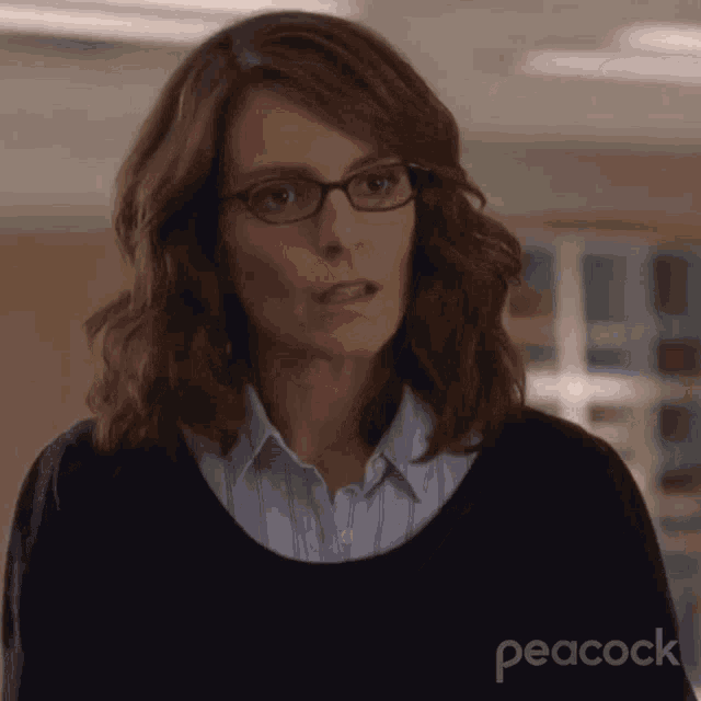 a woman wearing glasses and a black sweater with peacock written on the bottom